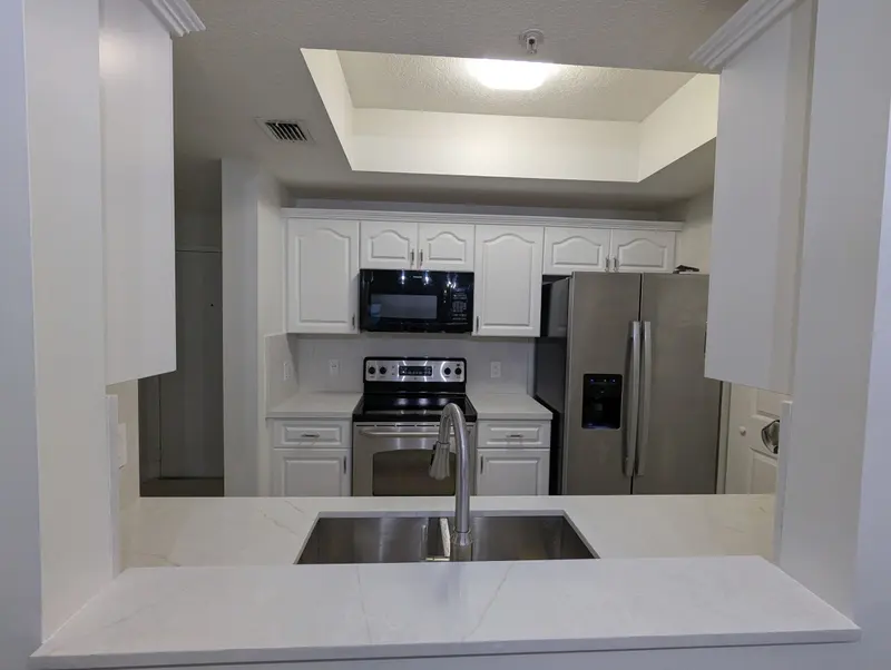 After: view of the white kitchen and new countertops through the pass-through, Coral Gables