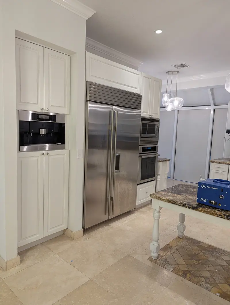 Aventura kitchen after painting, white cabinets beside the stainless steel refrigerator