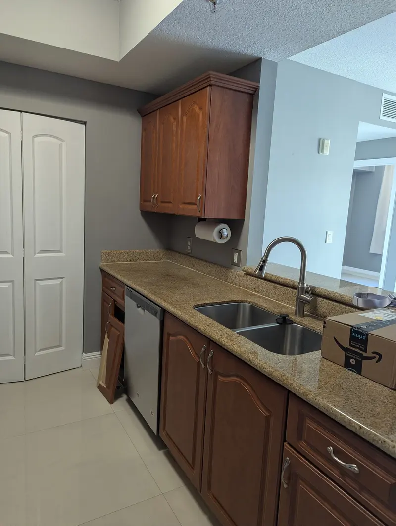 Before painting: sink wall with wood-grain cabinets and granite countertop, Coral Gables