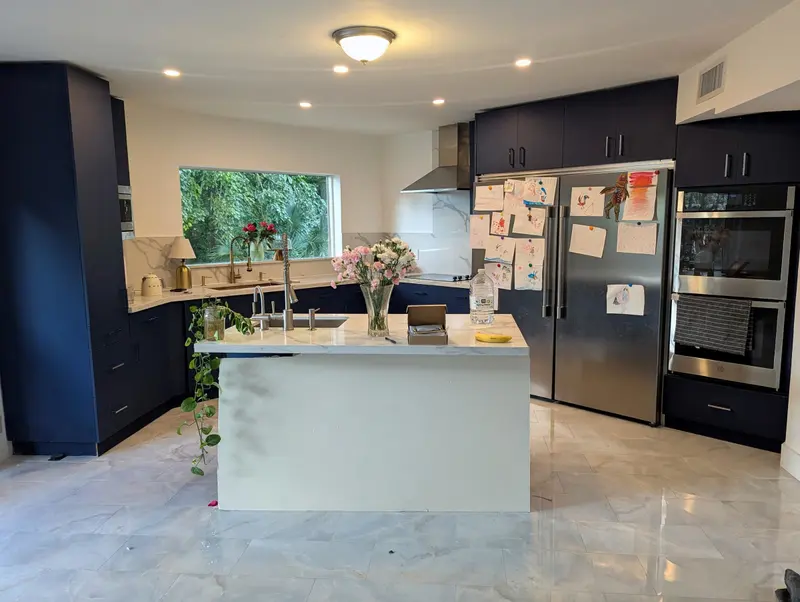 Fort Lauderdale kitchen before painting, worn navy cabinets around a white quartz island