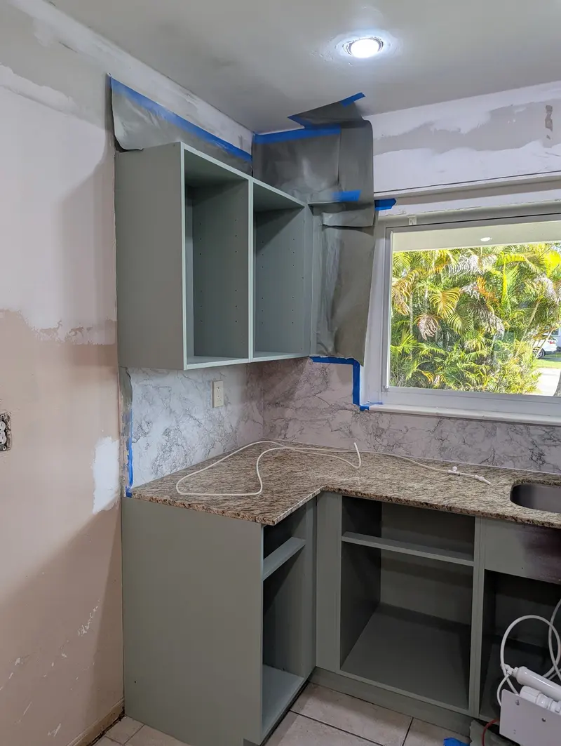 Refinished upper and base cabinet boxes beside the kitchen window, North Miami